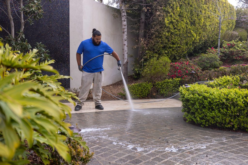 Six Shooter professional pressure washing concrete in blue shirt and khaki pants